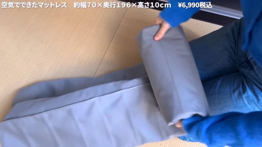 空気を抜いたマットレスを丸める様子