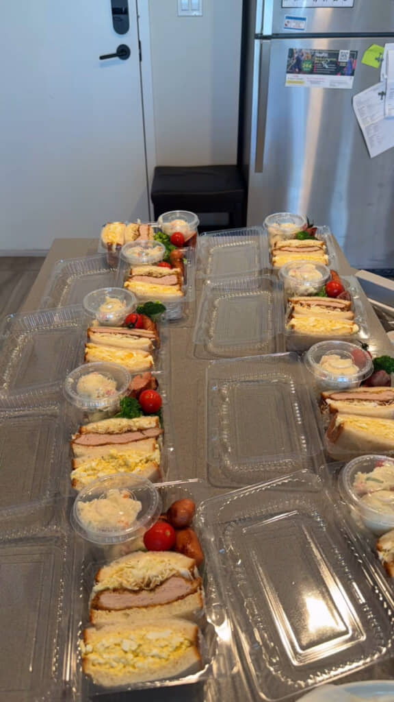 サンドやおかずを透明パックに詰める