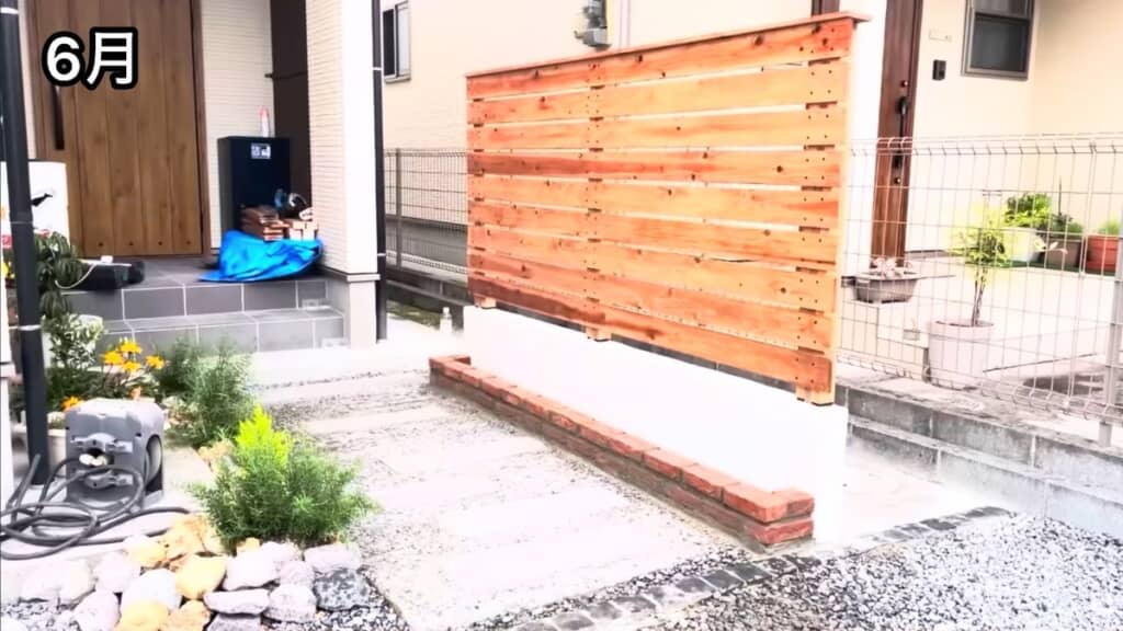 コンクリート仕上げにしてウッドフェンスを設けた隣人の玄関前