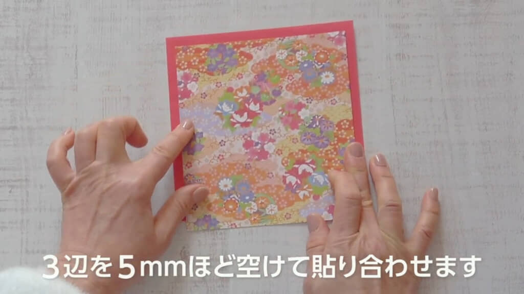 1辺を1センチ折った和柄の折り紙と、単色折り紙を重ねて貼り合わせたところ
