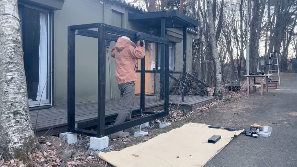 棚の骨組みを持ち上げて基礎の上に置く