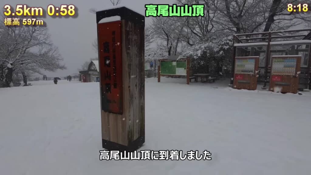 雪の中に立つ高尾山頂の看板