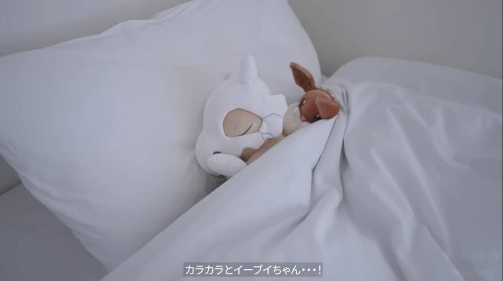 涙を流しながら眠るカラカラと、それを慰めるように寄り添うイーブイのぬいぐるみが……