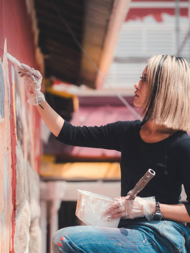 飲食店の壁面に絵を描いている投稿者を真横から撮った写真