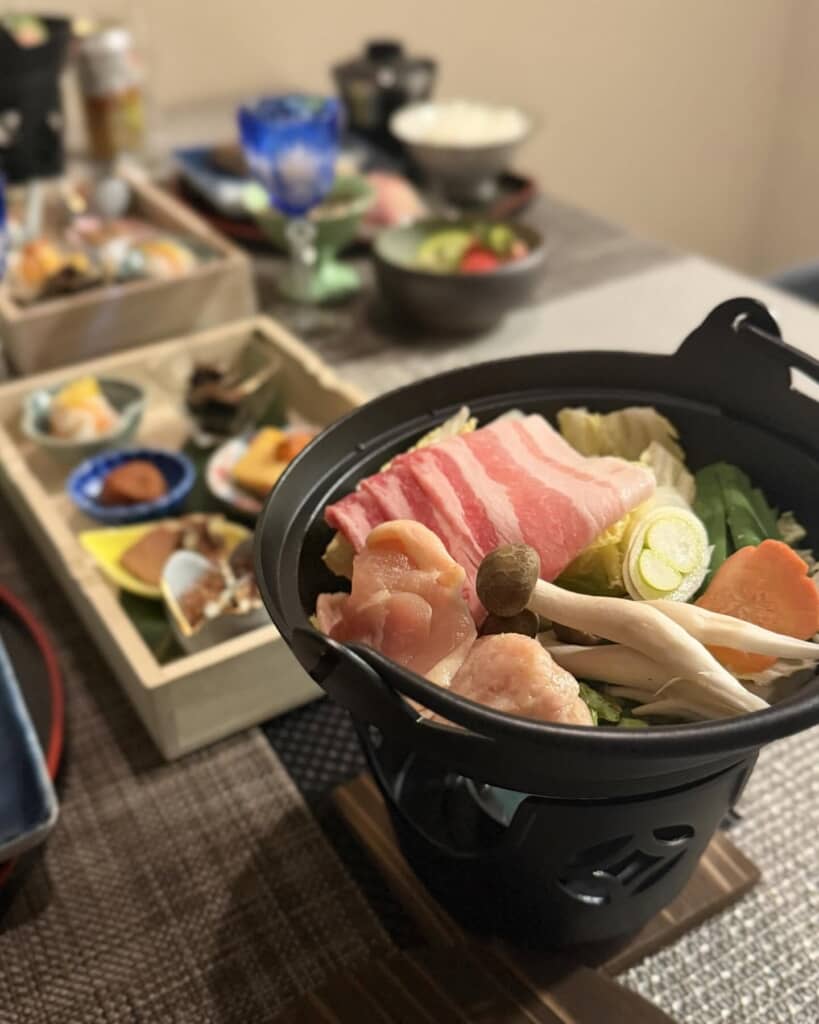 肉と野菜の小鍋や刺身、焼き魚など豪華な和食御膳のクローズアップ