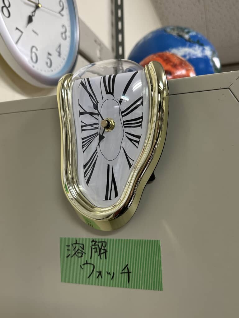 棚の角に置かれた「溶解ウォッチ」というラベル付きの溶けた形の時計