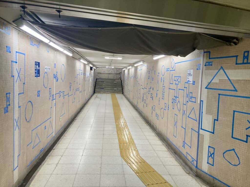 通路の両サイドの壁面いっぱいに貼られた青いテープ