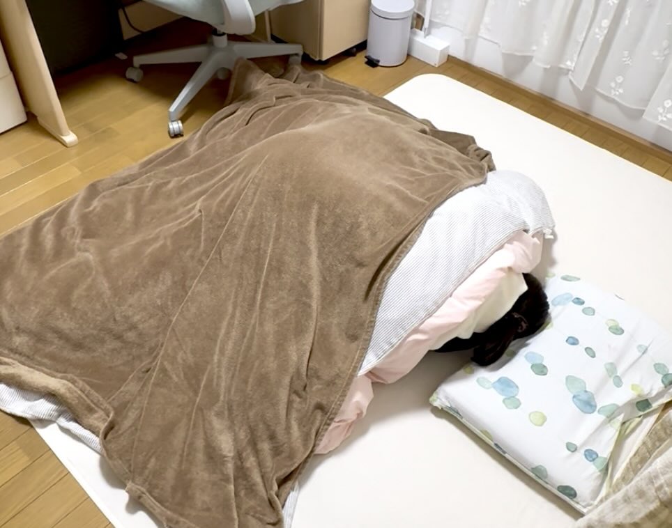 親子げんかの後、床で寝ている娘に布団をかける母