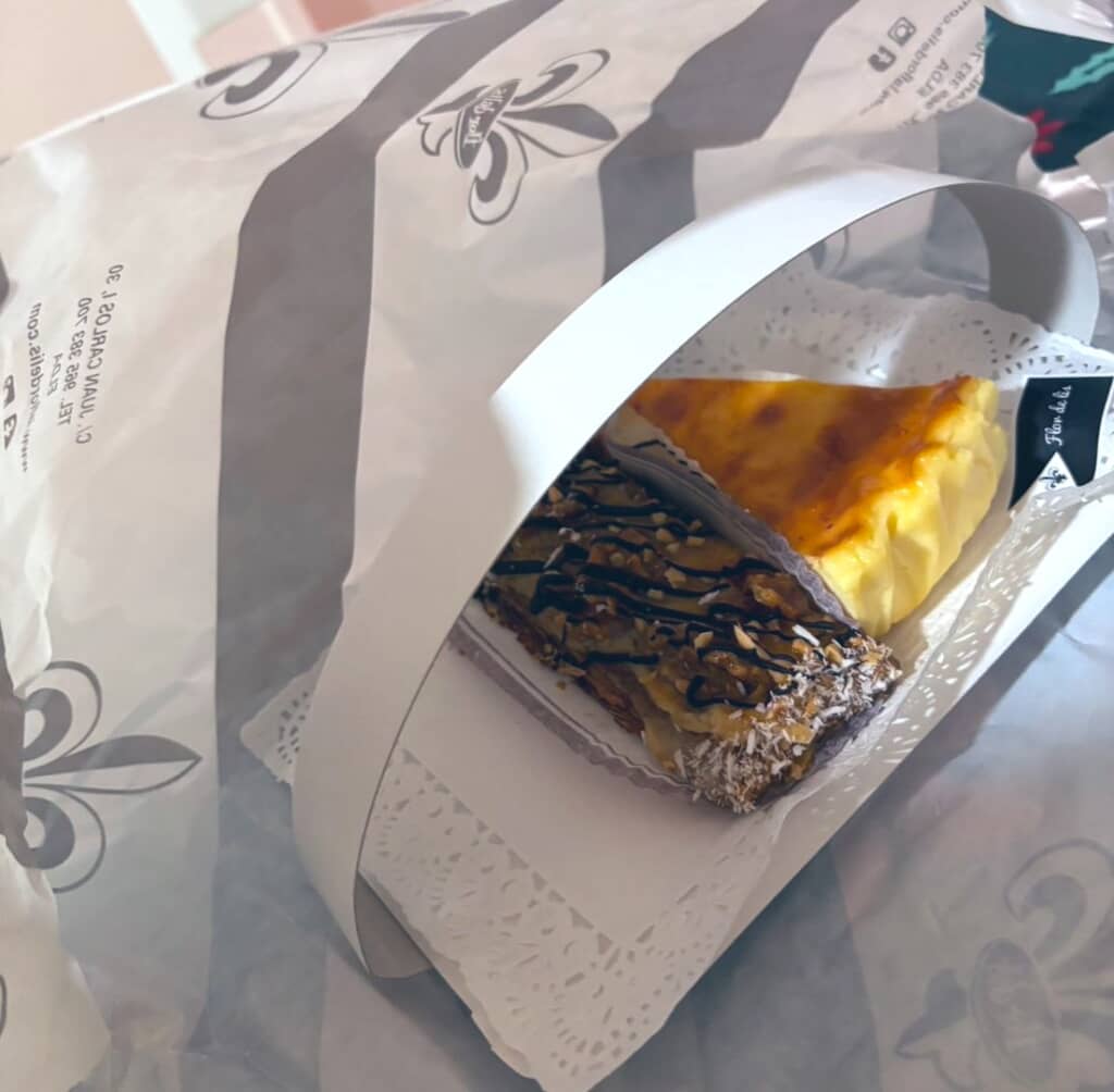 紙袋に入れられたカットケーキとナッツ入りの四角いケーキ