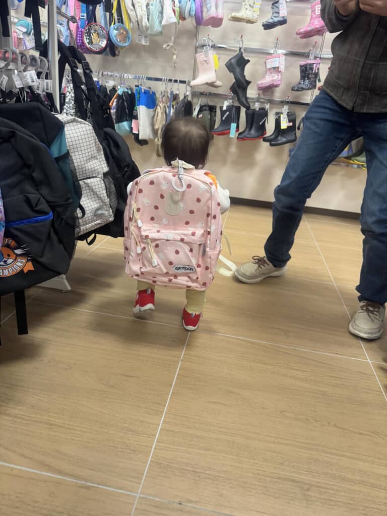 お店でピンク色の大きなリュックを背負って歩く幼児の後ろ姿