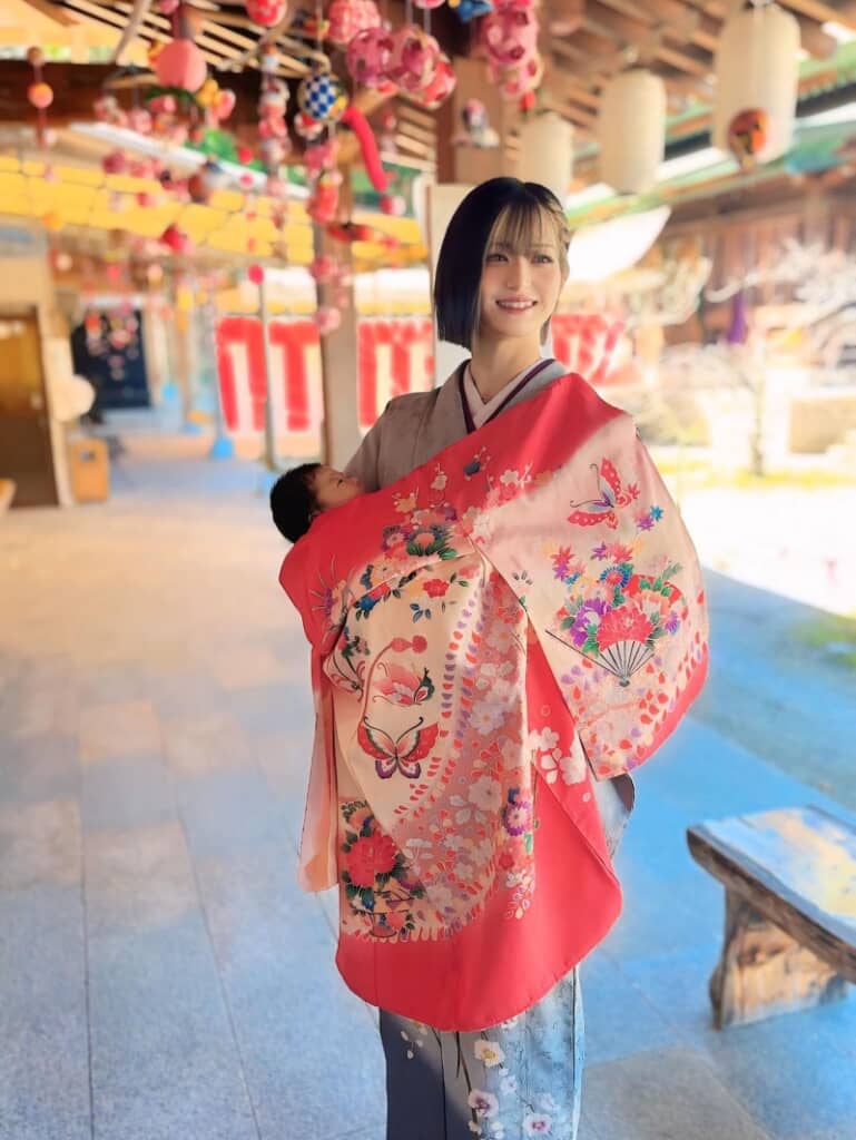 つるし雛の前で笑顔を見せています