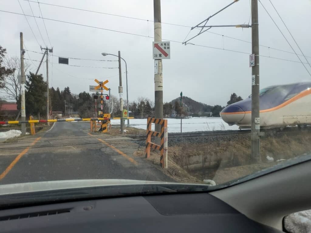 踏切を通過する山形新幹線・つばさを車内から撮影した写真