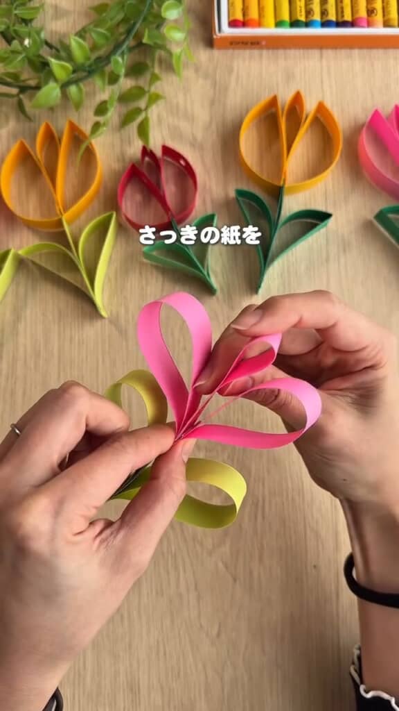 ピンクのほうも同様に曲げ、短いピンクの帯を中心へ。こちらも花の根元で留める