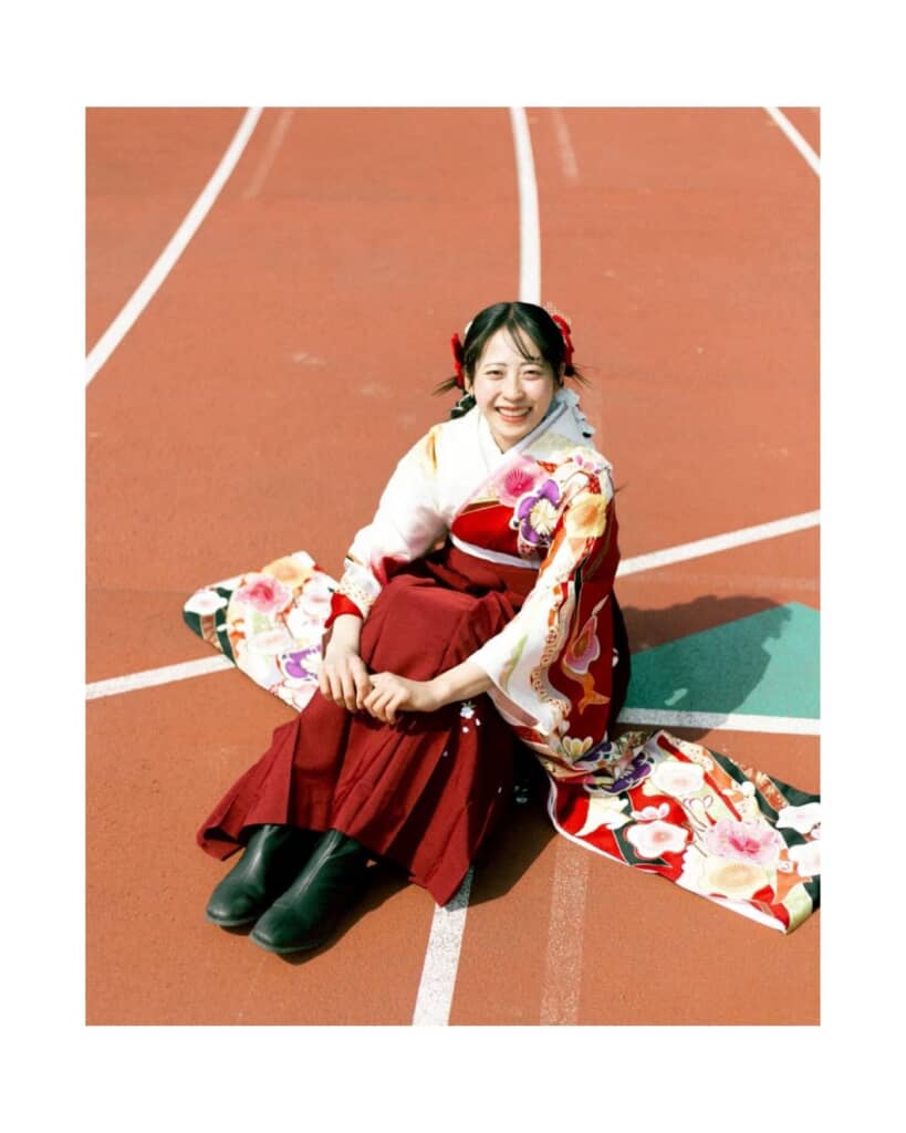 袴姿で陸上競技場のコースの上で体育座り