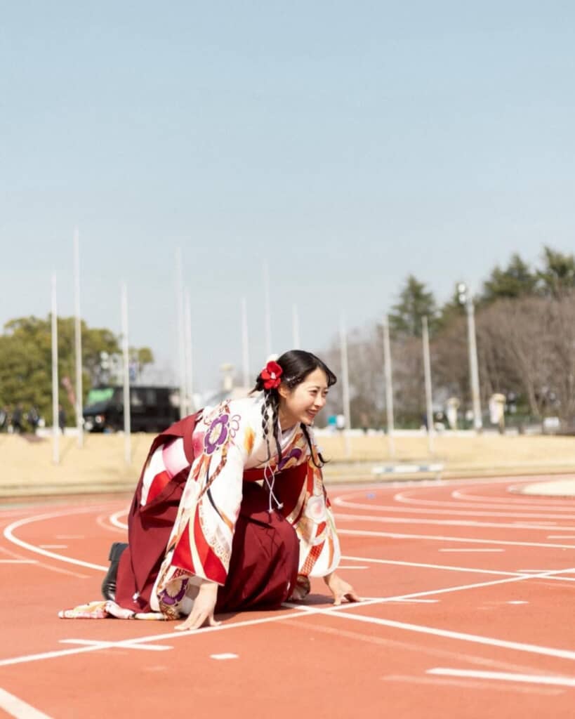 袴姿で陸上競技場でクラウチングスタートの構えをする女性