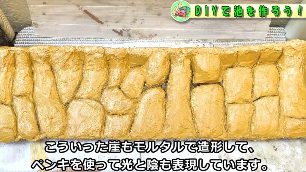 黄色く塗装された崖っぽい見た目のモルタル仕切り