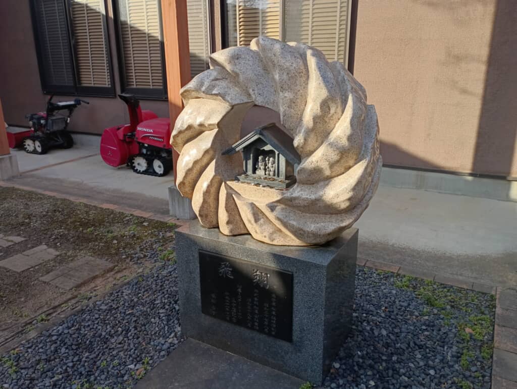 フレンチクルーラーの石彫の中に小さな祠が安置された石碑