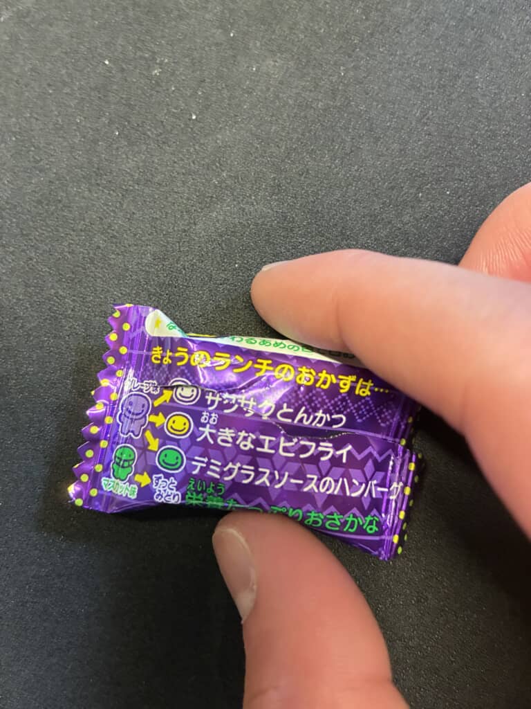 「きょうのランチのおかずは…」と書かれた紫色のキャンディの個包装