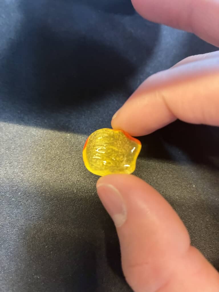 指先でつまんだ黄色い半透明の飴