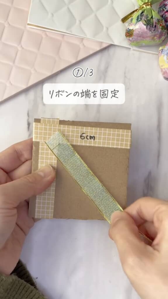 6センチ四方に切った段ボールに針を刺し、リボンを固定