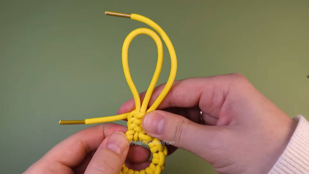 輪っかの根本でひもを編んでいく
