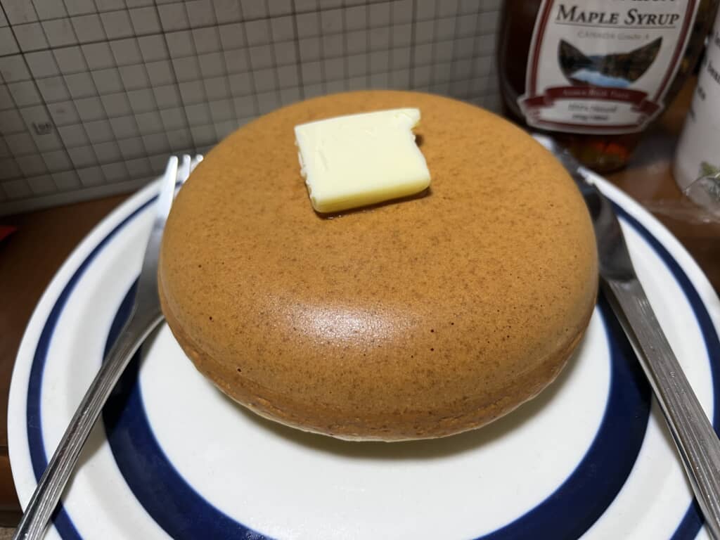 バターをのせた厚焼きホットケーキとメープルシロップの瓶