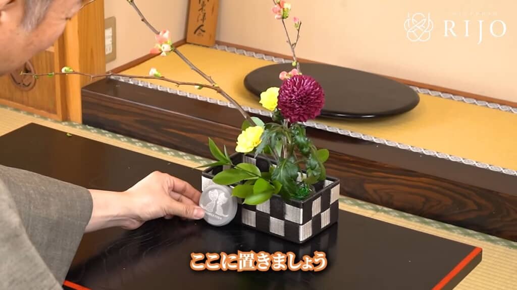 ネコが描かれているガラス瓶のフタをバスケットに立て掛ける