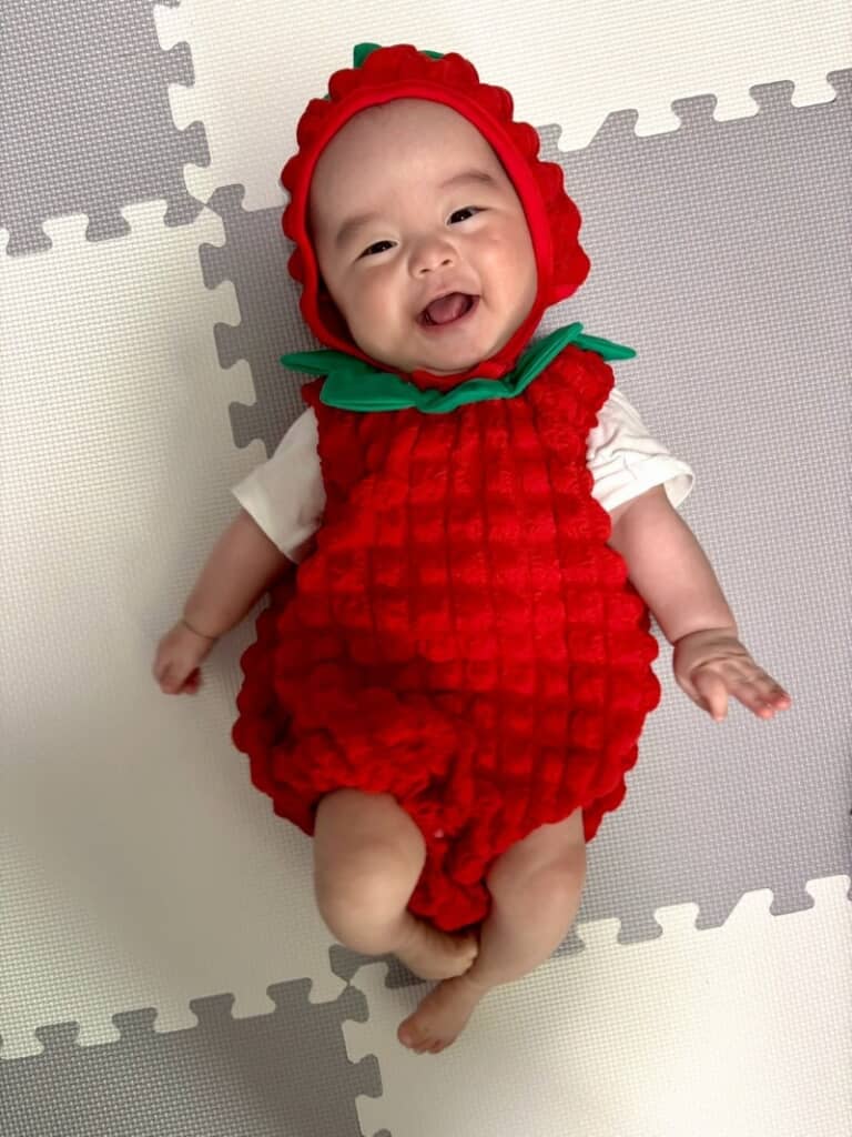 いちごのボディスーツを着てとびっきりの笑顔を見せてくれる息子くん