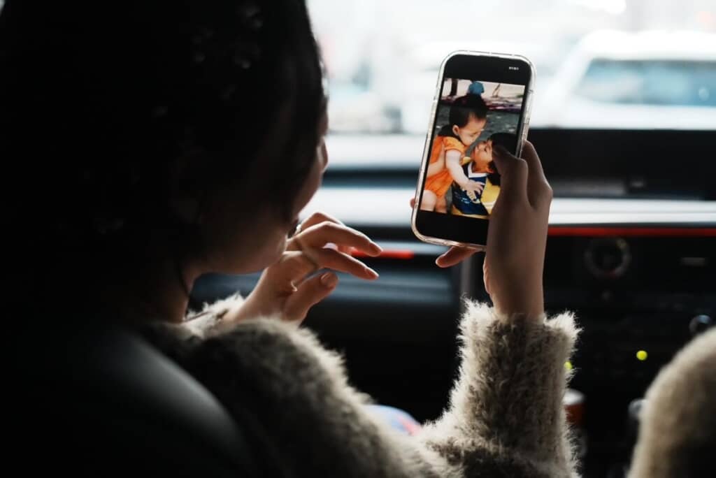 スマホで思い出の写真を見る妻