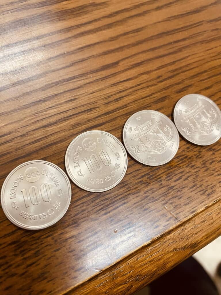 裏面と表面を2枚ずつ並べた沖縄国際海洋博覧会記念100円白銅貨幣の写真
