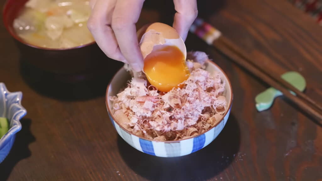 ごはんの上にかつお節と生卵の黄身をのせる
