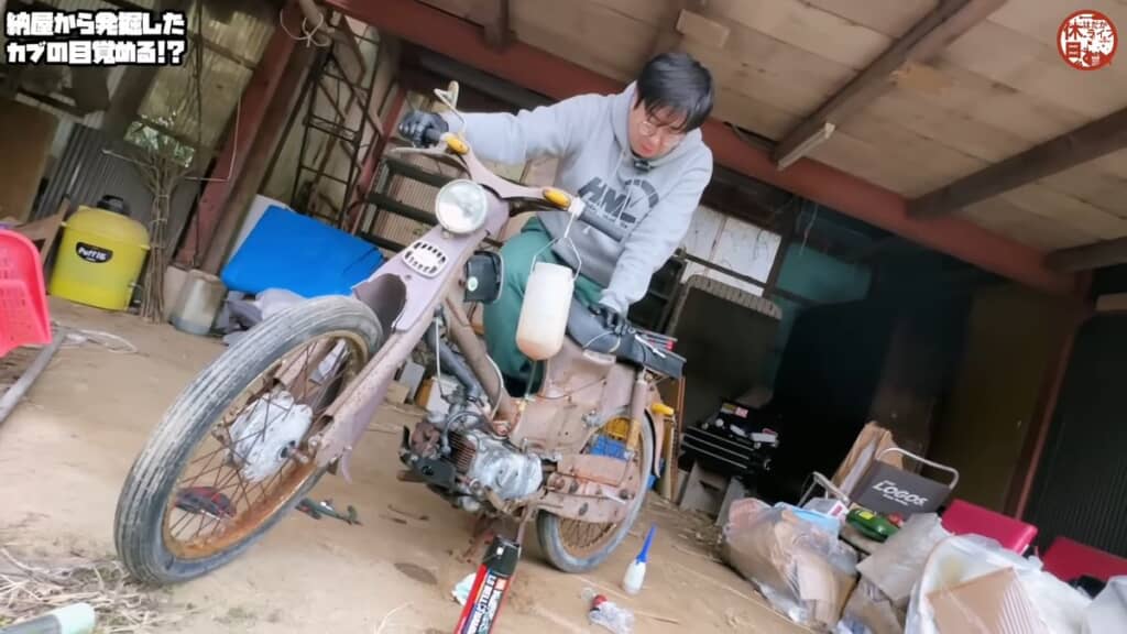 キックスターターを踏み込んでエンジン始動を試みる父親