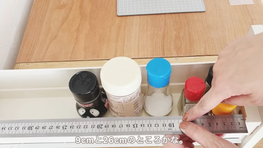 仕切り板を引き出しのどこに付けるか、定規を当てて考えている