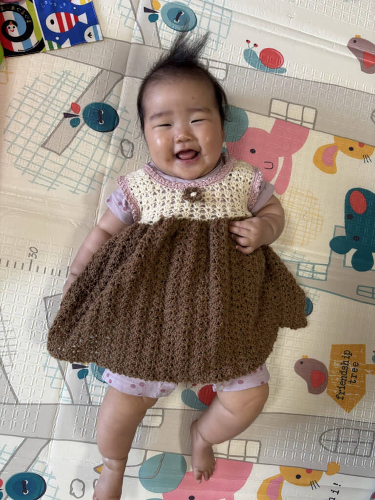 家族はもちろん、ご近所さんにも愛されている赤ちゃん。手編みのワンピースを着せてもらってご満悦