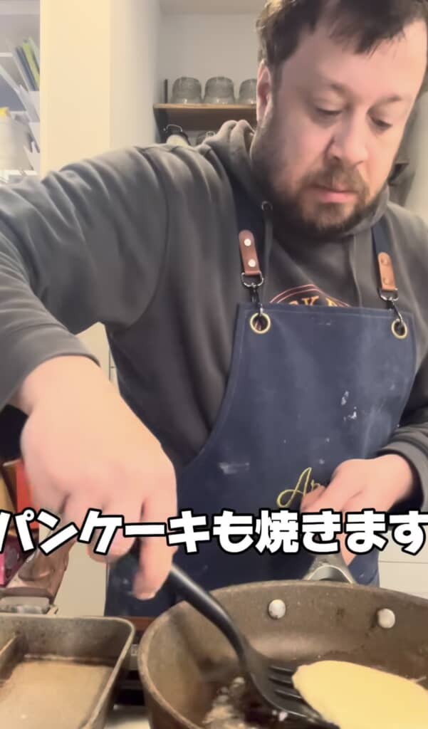 "Aruchan"エプロンの男性がフライパン2つでパンケーキを焼く様子