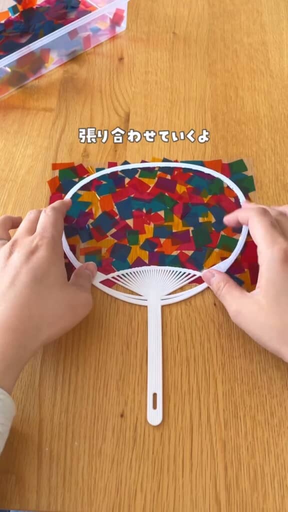 うちわに瞬間接着剤でラミネートフィルムを貼り付け。反対側から挟むように、無地のフィルムも貼ります