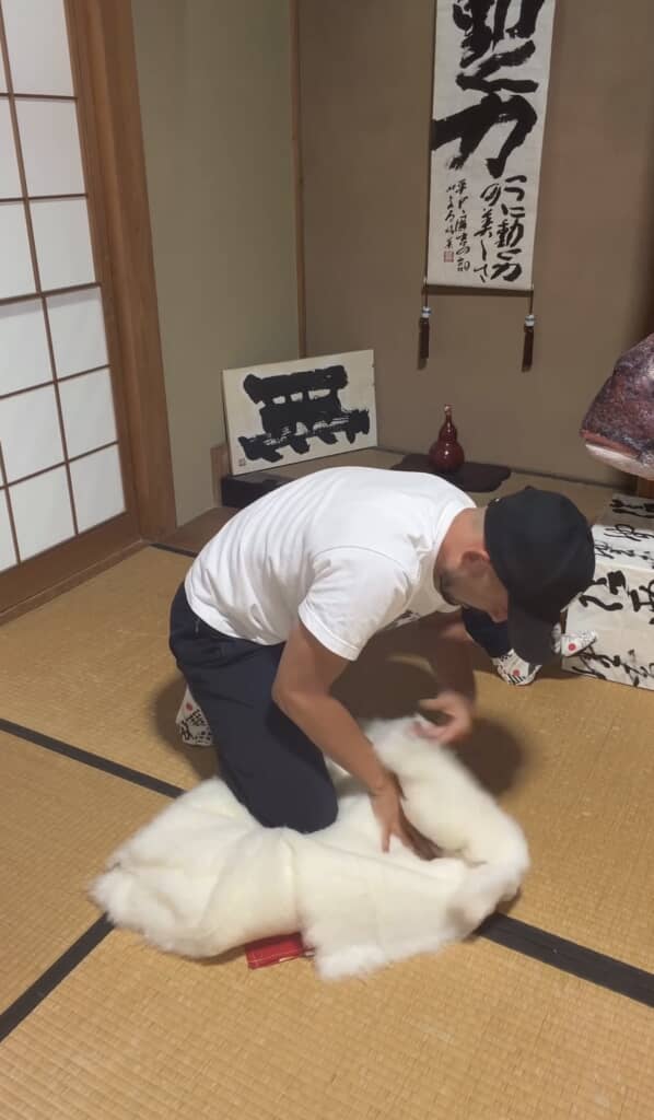 赤い布の上に白い綿を広げて丁寧に作業する男性