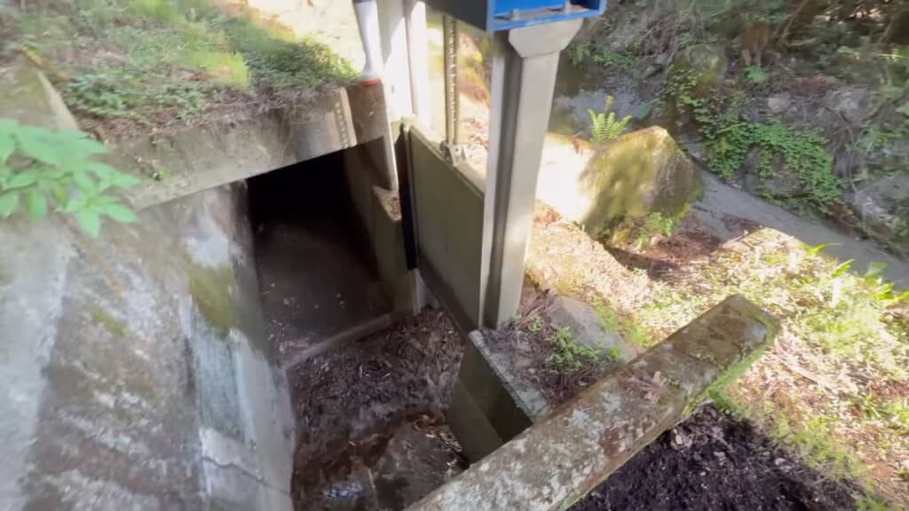 放水門を通って谷へと流れていくゴミだらけの水