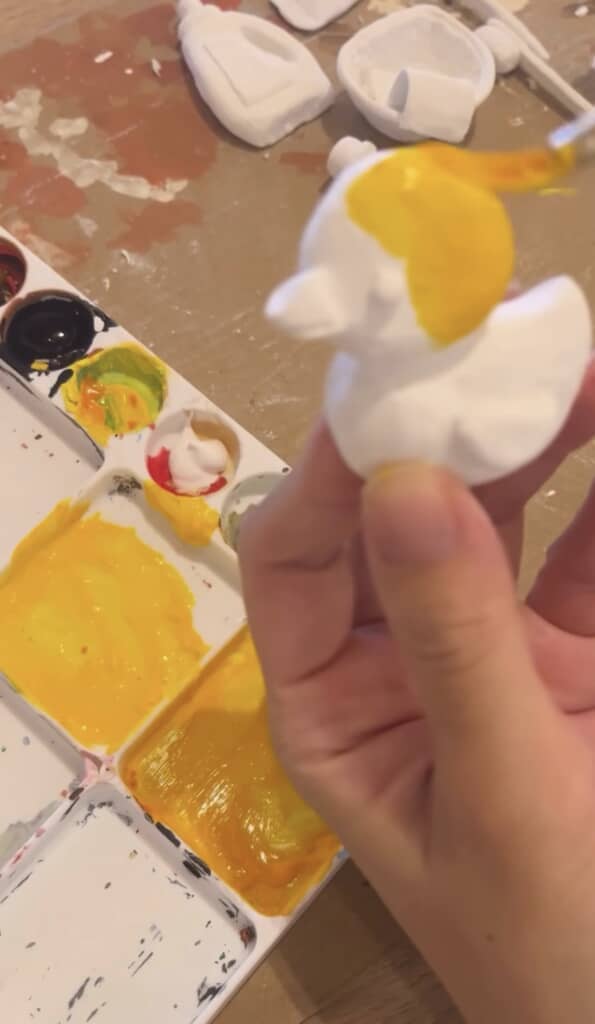 粘土に黄色い絵の具を塗る様子