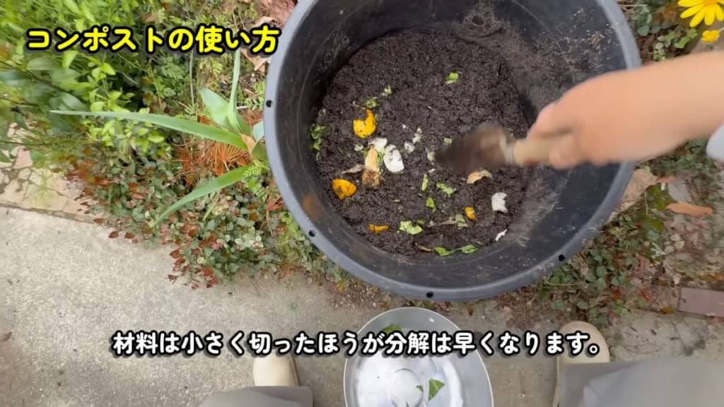 コンポスト内の土に野菜くずを混ぜ込む様子