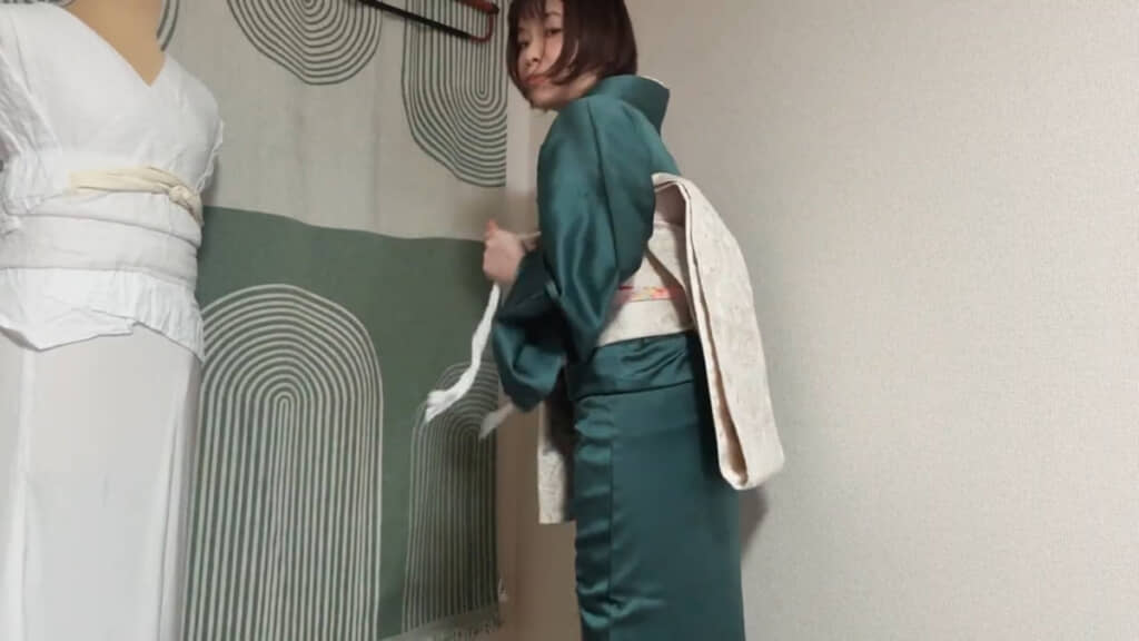 帯枕のひもを引っ張ってしっかり背中に当てます