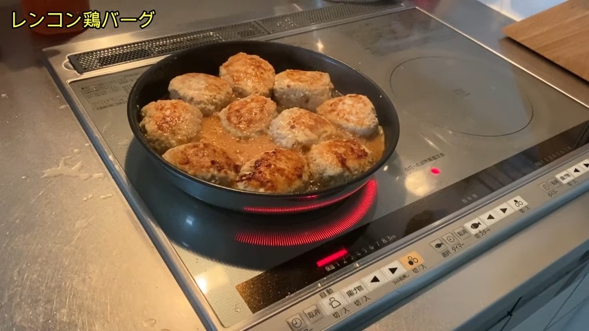 鍋の中に並べて入れたハンバーグに、たれ（醤油、砂糖、酒、みりん）を入れてからめている