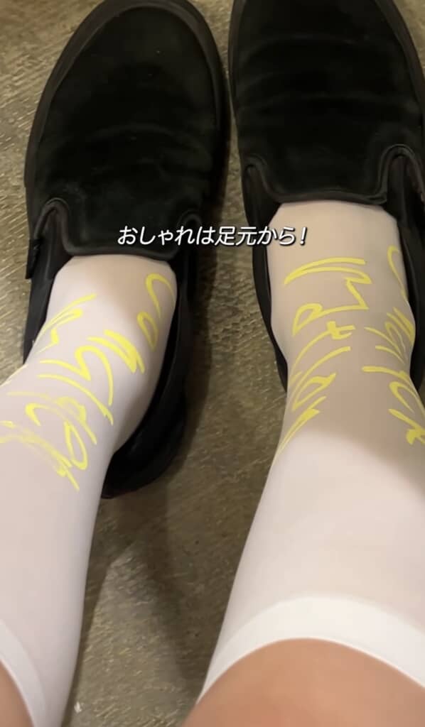 「おしゃれは足元から!」の字幕と黄色いロゴ入り白靴下と黒ローファーのコーデ