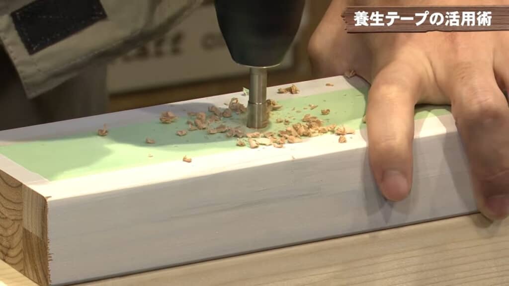 養生テープを貼った木材にドリルで穴をあける様子