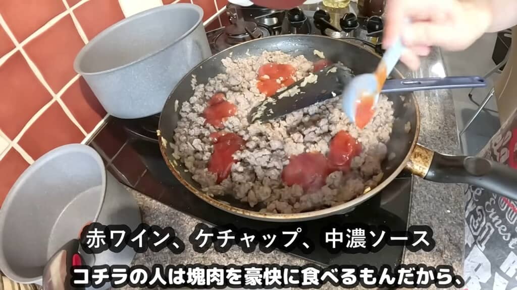フライパンでひき肉に赤ワインとケチャップ、中濃ソースを加えて炒める調理風景