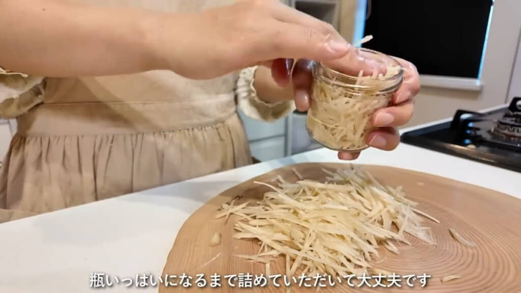ビンいっぱいになるまでショウガを詰めています