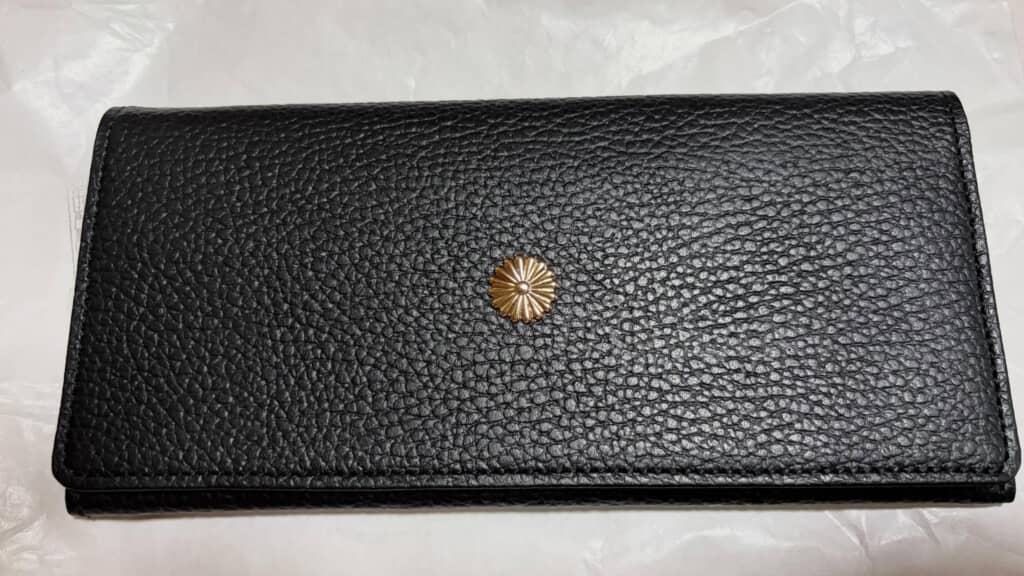 黒い長財布、正面に金色の菊花デザインの金具