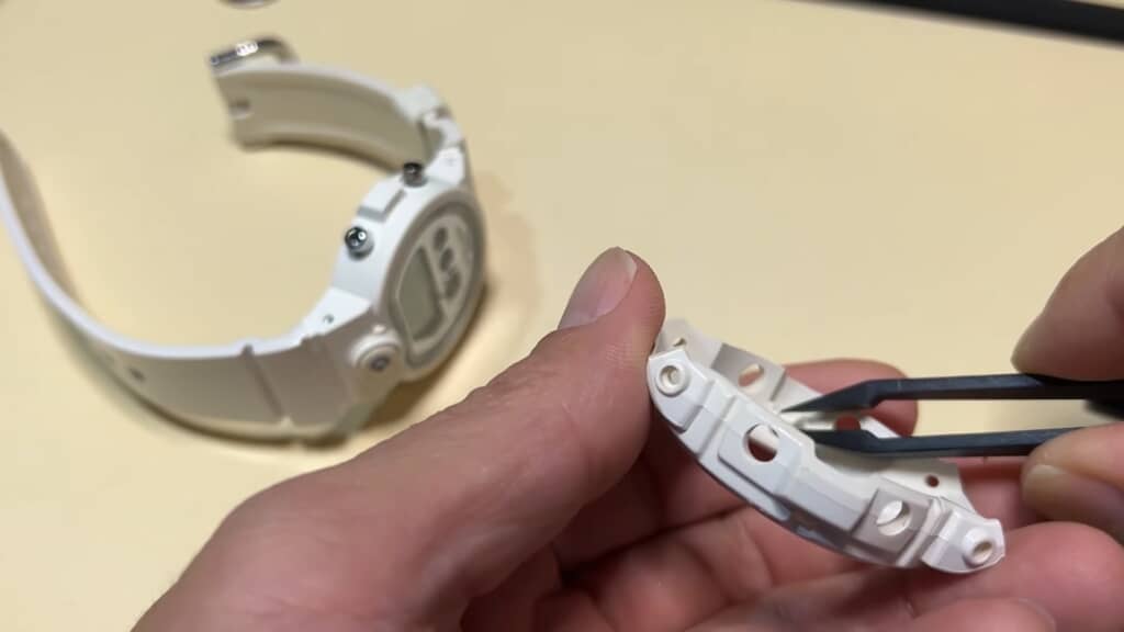 白いバンドのコマ部分をピンセットで分解する作業