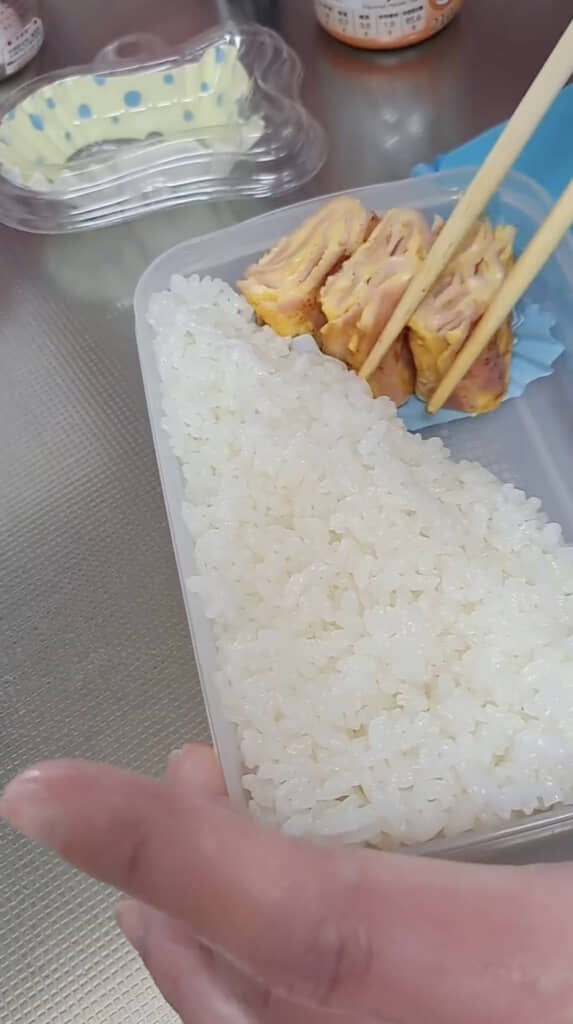 白米を詰めた容器におかずを盛り付けて……