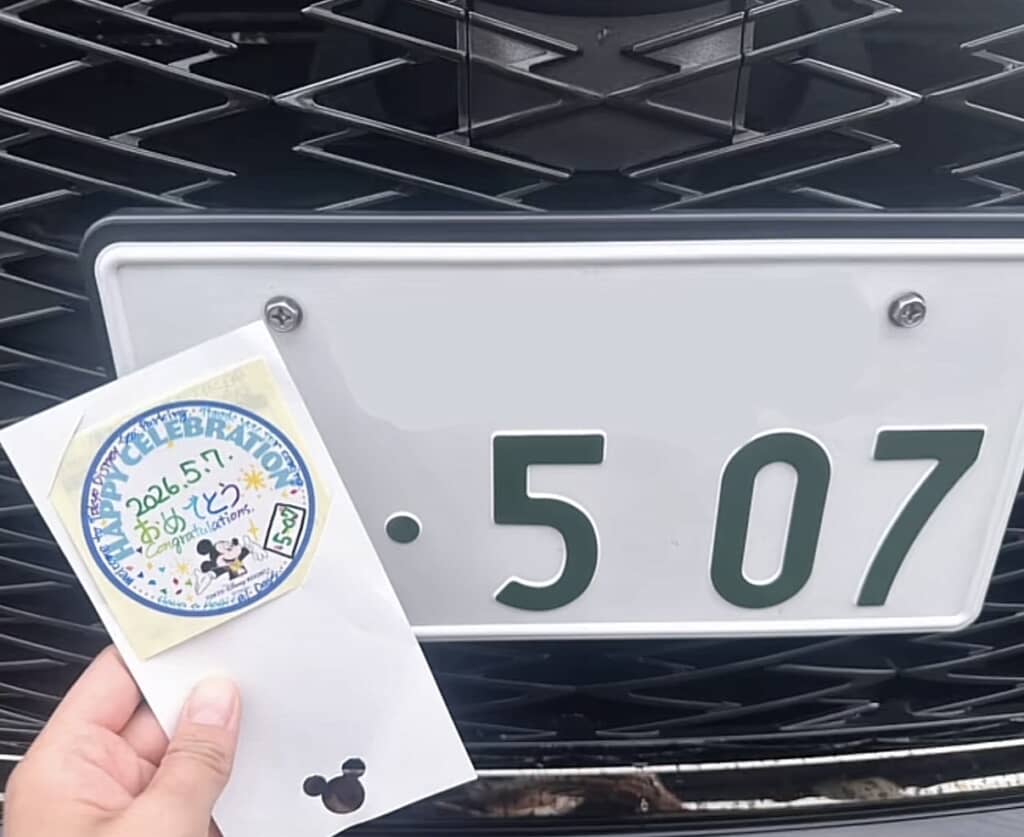 手に持ったディズニーシーステッカーと車のナンバープレート507